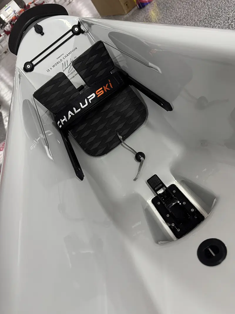 The cockpit of a ChalupSki surfski, showing the carbon footplate and the adjustable footrest mechanism, the hull still in its delivery wrapping.